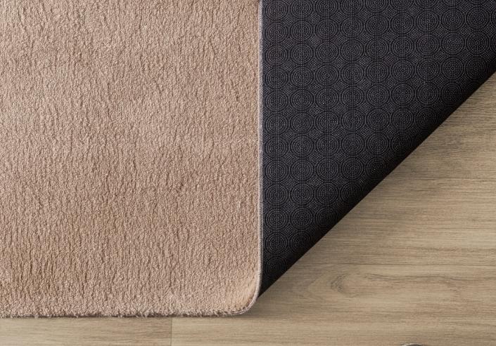 Détail du coin d'un tapis LOFT beige foncé montrant la finition robuste des bordures et la hauteur des poils.