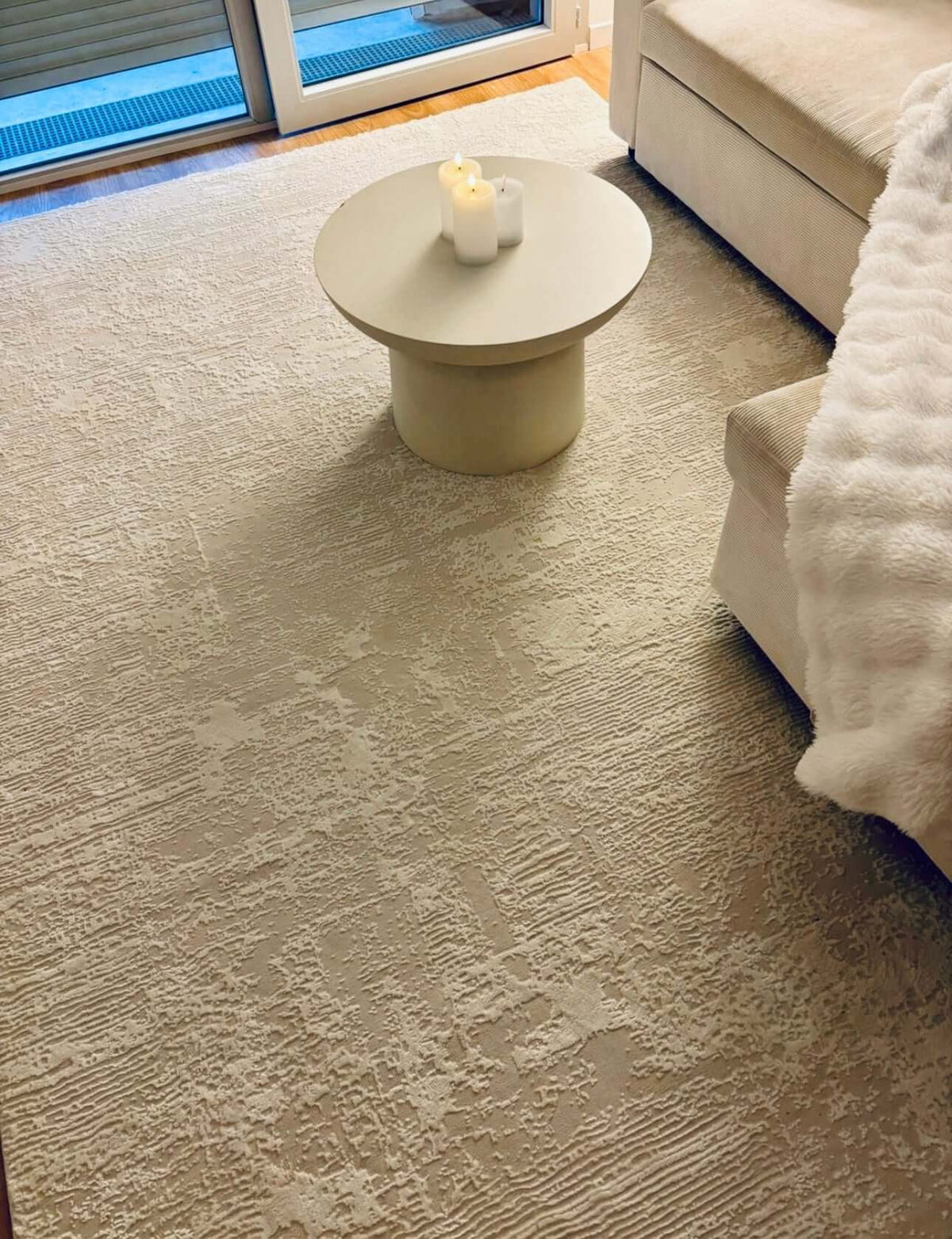 Tapis minimaliste SIGNO 05 crème avec motif de lignes en relief dans un salon lumineux au design contemporain.