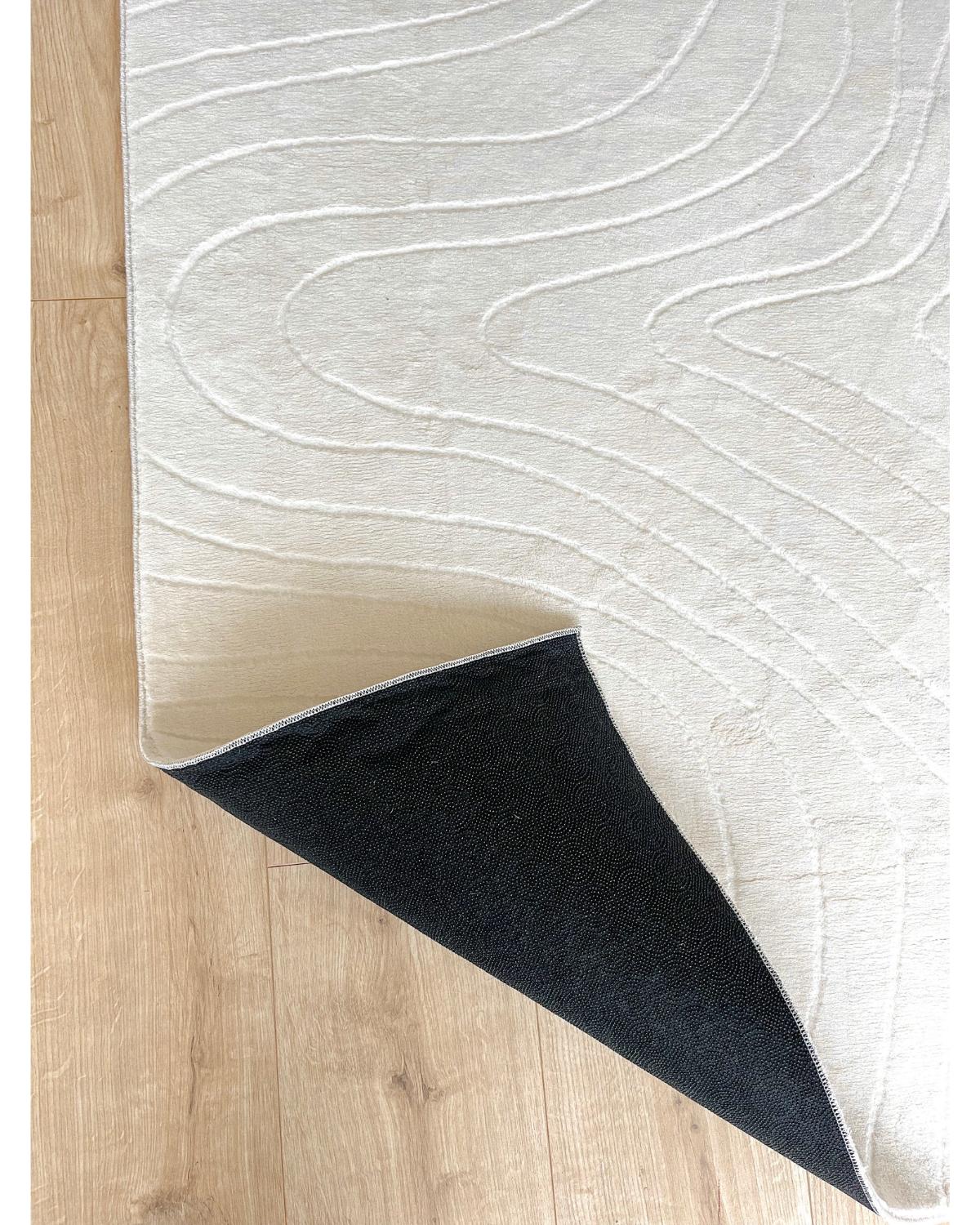 Vue en angle du tapis STILO 01 crème montrant l'épaisseur du relief 3D.