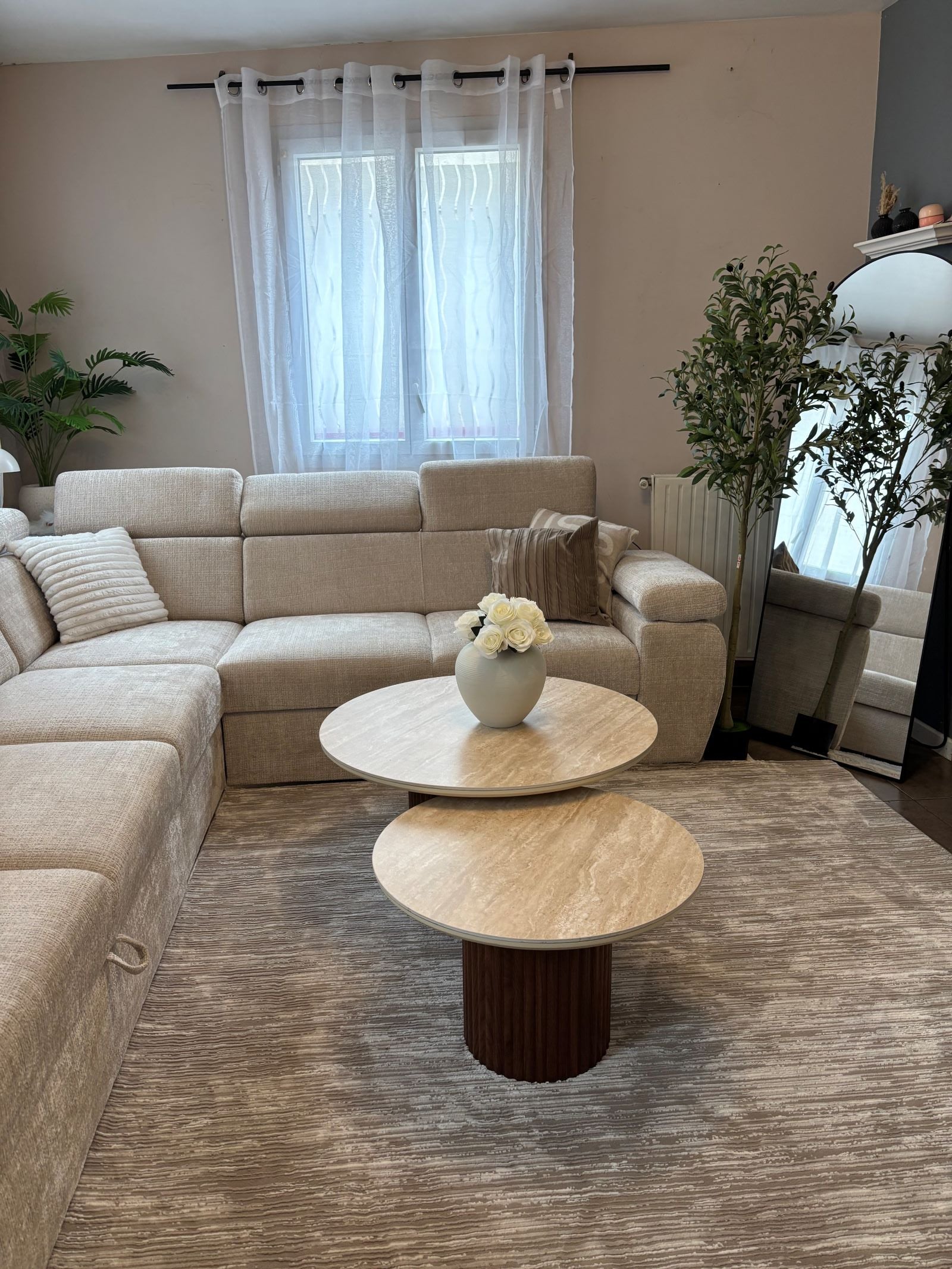 Tapis de designer avec relief linéaire taupe, mis en valeur par des tables basses gigognes en travertin.
