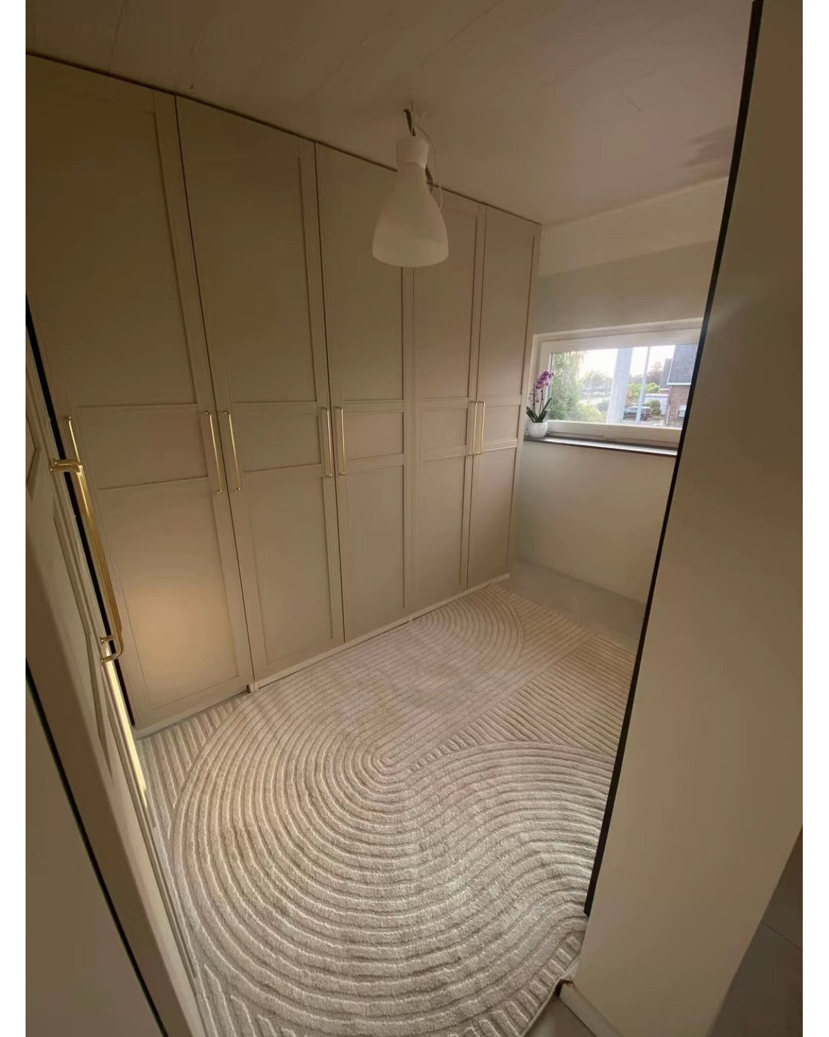 Tapis crème ELIO 51 avec motifs d'arches en relief dans un dressing au style moderne organique et épuré.