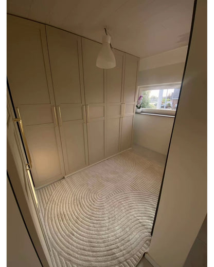 Tapis crème ELIO 51 avec motifs d'arches en relief dans un dressing au style moderne organique et épuré.