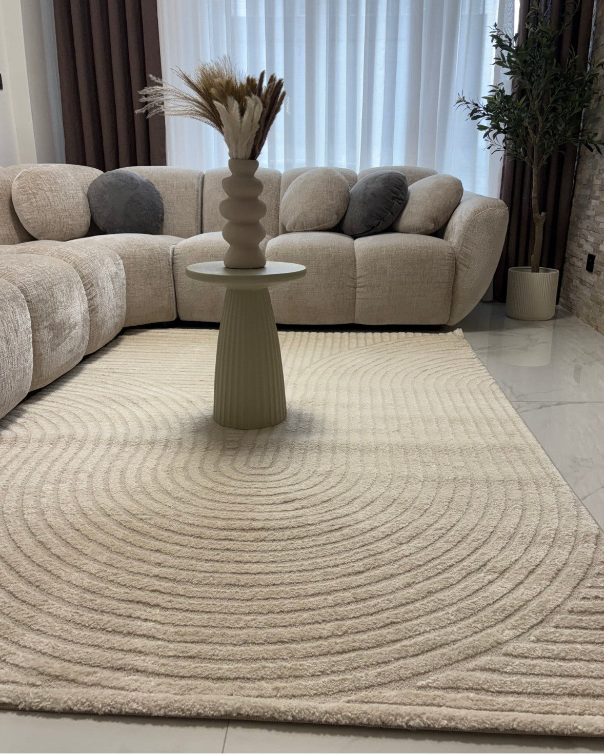 Tapis crème ELIO 51 avec motifs d'arches en relief dans un salon au style moderne organique et épuré.