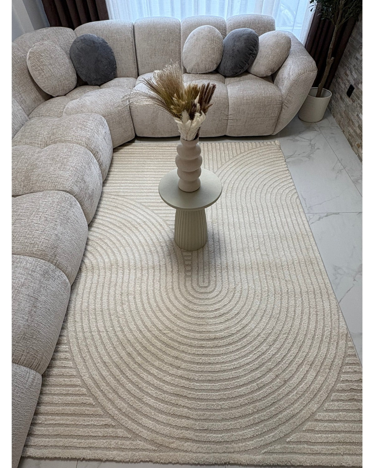 Tapis crème ELIO 51 avec motifs d'arches en relief dans un salon au style moderne organique et épuré.