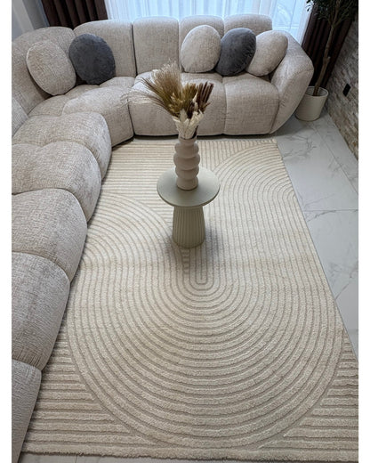 Tapis crème ELIO 51 avec motifs d'arches en relief dans un salon au style moderne organique et épuré.