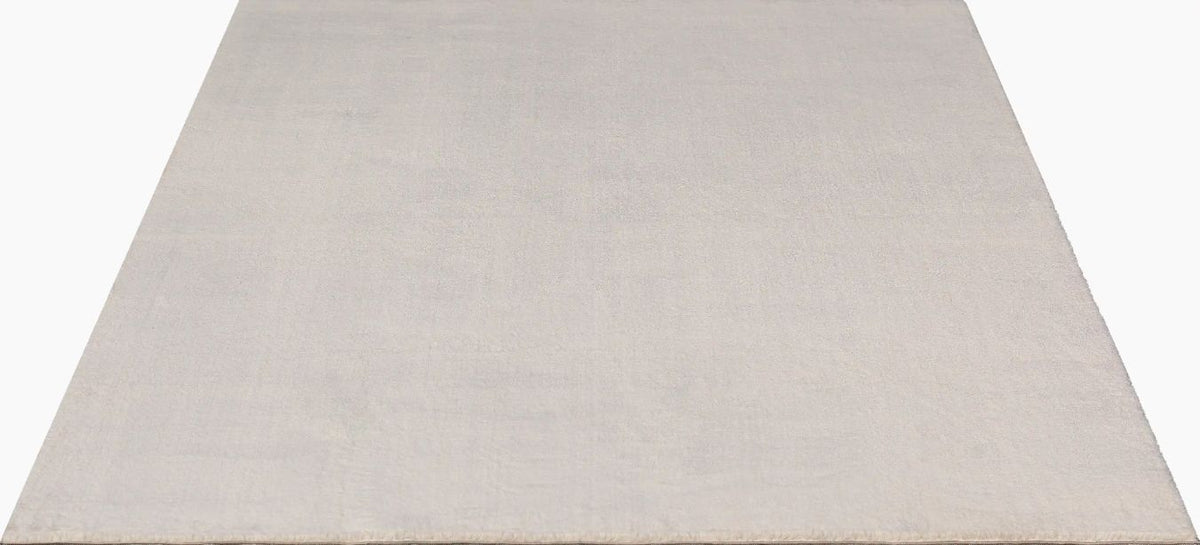 Tapis rectangulaire LOFT beige présenté sur fond blanc uni, montrant la couleur blanc cassé pure et la texture dense à poils hauts.