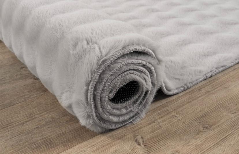 Détail en gros plan sur le tissage du tapis Bubble gris clair, montrant le contraste entre le fond plat et le relief sculpté et doux des bulles 3D.