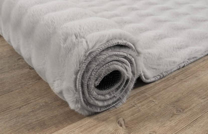 Détail en gros plan sur le tissage du tapis Bubble gris clair, montrant le contraste entre le fond plat et le relief sculpté et doux des bulles 3D.