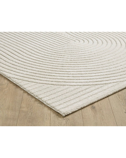 Gros plan sur les motifs en arc de cercle du tapis ELIO 51 crème, montrant le relief sculpté et la densité des fibres.