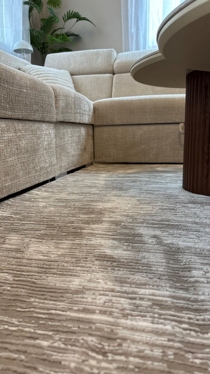 Zoom sur le relief et les rayures d'un tapis taupe haute qualité, montrant la structure et l'épaisseur des fibres.