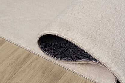 Démonstration du tapis LOFT beige plié pour le lavage en machine, prouvant qu'une couleur claire reste facile à entretenir.