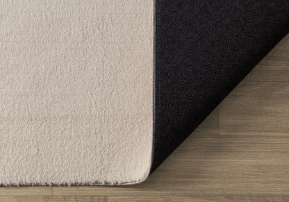 Démonstration du tapis LOFT beige plié pour le lavage en machine, prouvant qu'une couleur claire reste facile à entretenir.