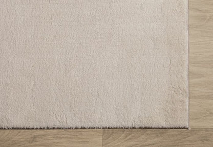Zoom sur l'angle d'un tapis LOFT beige illustrant la finition soignée des bordures et la densité des poils blancs cassés.