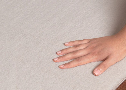 Main caressant les fibres soyeuses du tapis LOFT beige pour montrer le confort exceptionnel et l'épaisseur du modèle.
