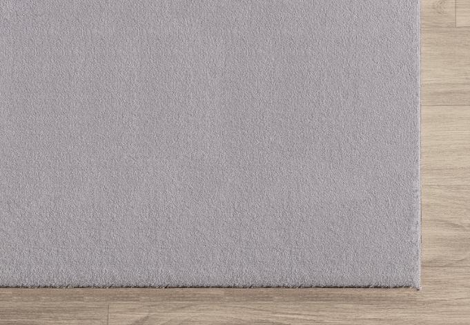 Zoom sur la bordure finie du tapis LOFT gris clair, montrant la densité des poils et la qualité du tissage.