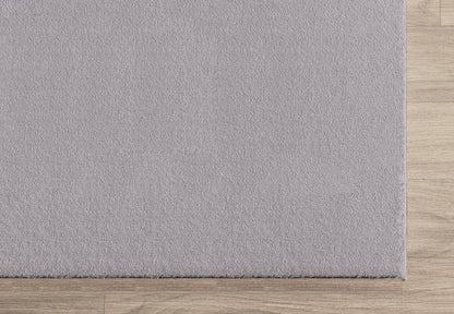 Zoom sur la bordure finie du tapis LOFT gris clair, montrant la densité des poils et la qualité du tissage.