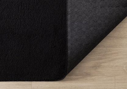 Tapis LOFT noir plié de manière compacte pour un passage en machine à laver, prouvant que le noir reste facile à entretenir et à garder propre.