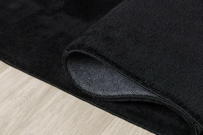 Tapis LOFT noir plié de manière compacte pour un passage en machine à laver, prouvant que le noir reste facile à entretenir et à garder propre.