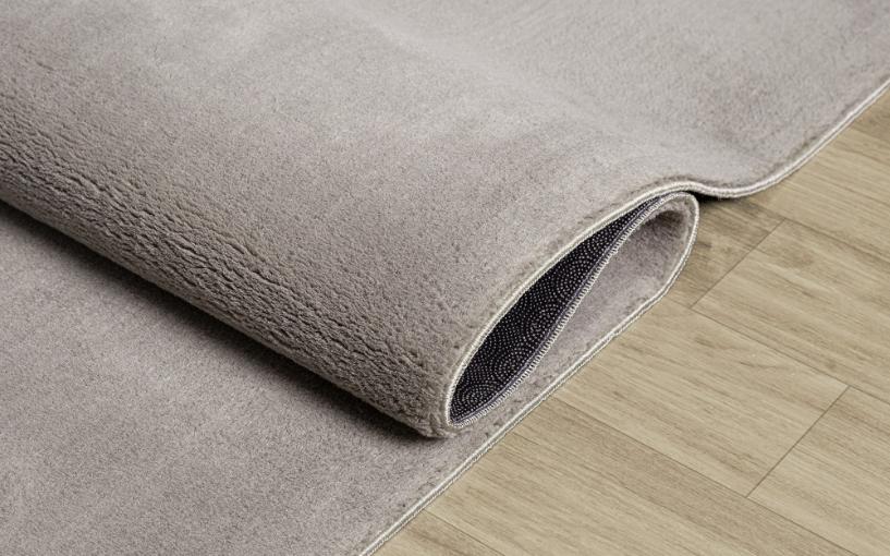 Tapis LOFT taupe souple et plié pour un lavage en machine facile, garantissant une hygiène parfaite au quotidien.