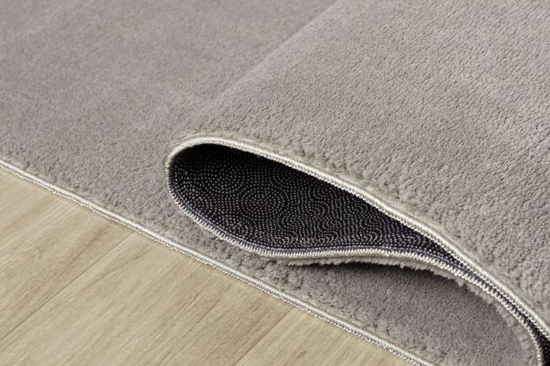 Tapis LOFT taupe souple et plié pour un lavage en machine facile, garantissant une hygiène parfaite au quotidien.