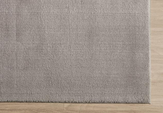 Zoom sur la bordure finie du tapis LOFT taupe, montrant la densité des poils et la qualité du tissage.